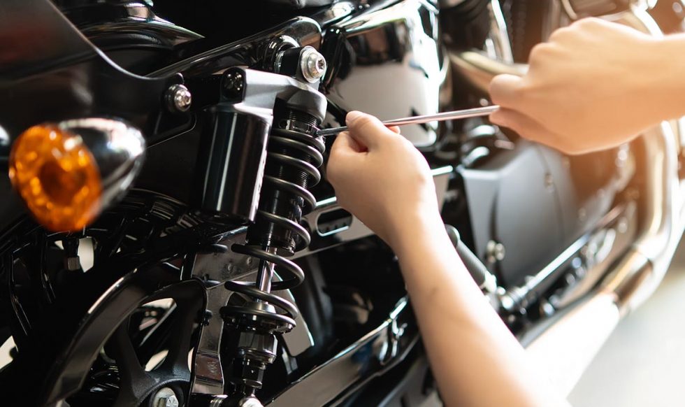 Mechanic using Tools set up suspension sag Compression and Rebound on a motorcycle in garage,maintenance motorcycle concept .selective focus